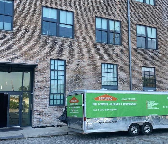 large green SERVPRO trailer parked outside of a tall brick building